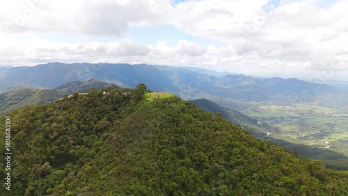 aerial and circular view of a mount at the top in the middle of the Atlantic Forest in Sao Paulo coast in Brazil with mountains at distance