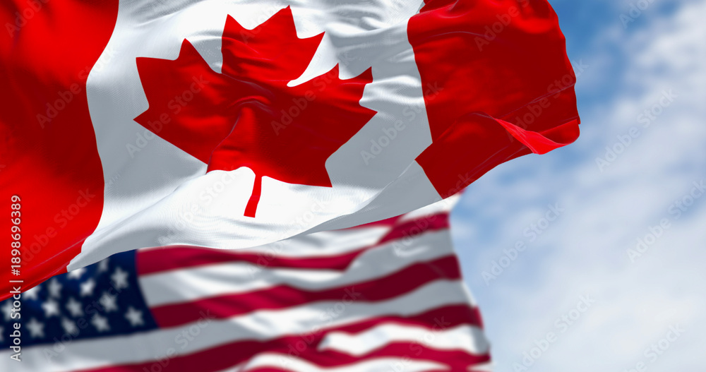 Fototapeta premium Canada and american national flags waving in the wind on a clear day