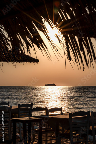 Beautiful sunset at the Aegean sea, Samothrace or Samothraki island Greece, tree and ship or boat silhouette, enjoying summer vacation, wellness and tourism, restaurant on the beach