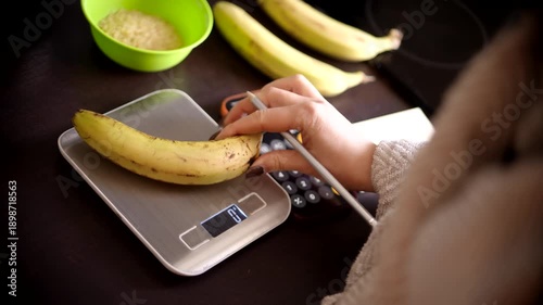 Nutritionist Weighing Banana On Electronic Kitchen Scale. Counting Calories With Smartphone Calculator. Healthy Diet Planning