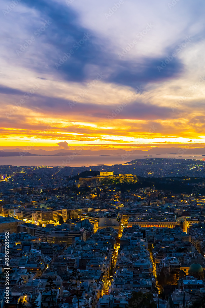 Obraz premium Panorama of Athens at sunset with a view of the Acropolis. The city lit up at night against the backdrop of enchanting clouds and a mesmerizing sunset. A peaceful picture of relaxation 