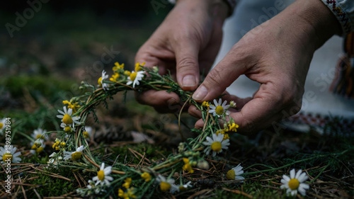 Ivan Kupala midsummer tradition - hands weaving wildflower wreath in meadow