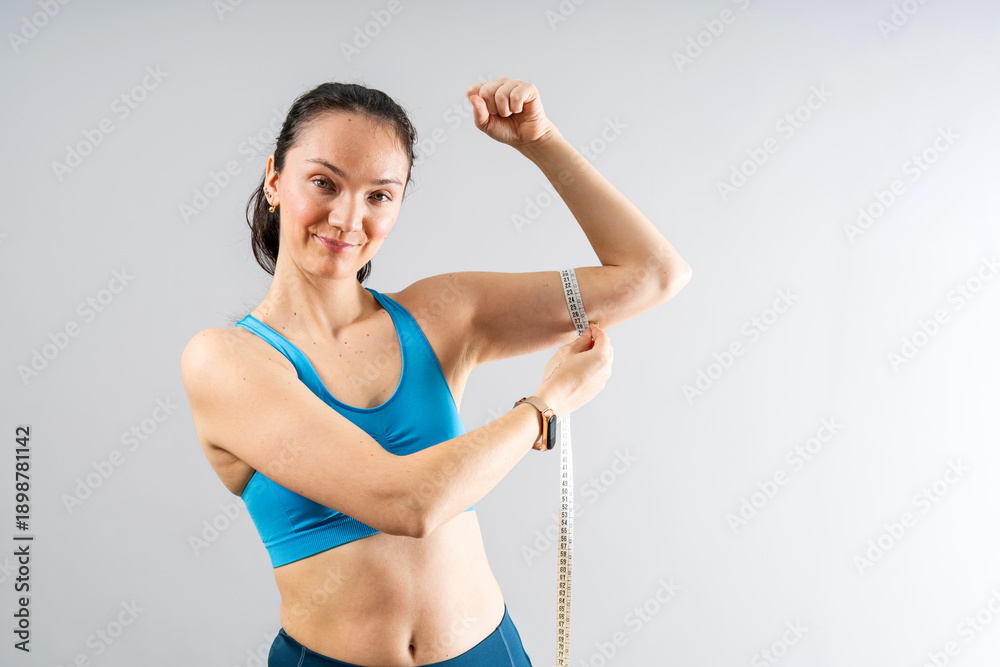 Fototapeta premium Woman measuring bicep for fitness progress