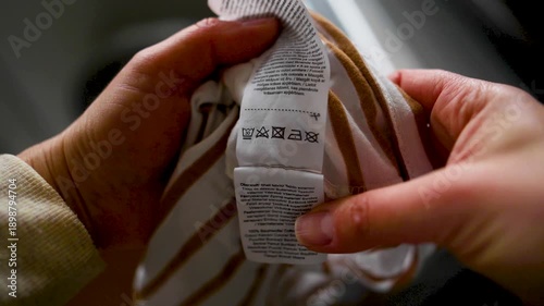 Woman reading clothing label with care symbols and information on clothing near washing machine, closeup