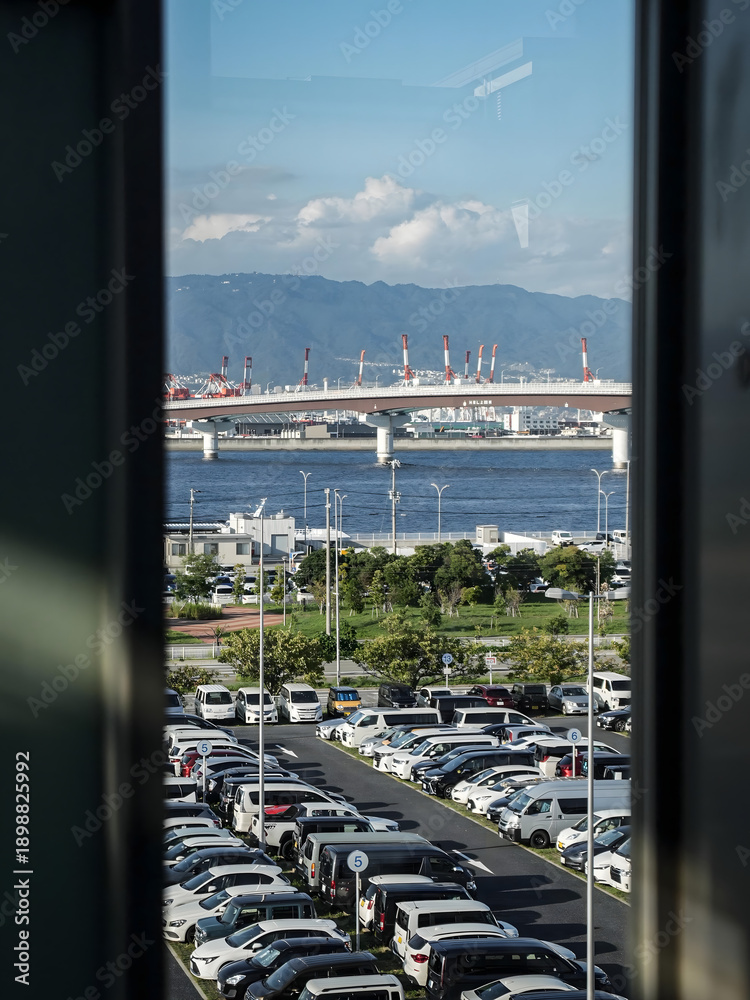 Naklejka premium Kobe Harbor View with Parked Cars and Industrial Bridge
