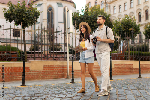 Obraz na plátně Happy man and woman tourists strolling along cobblestone path in the city, lady