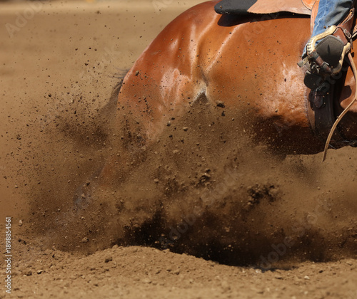 A barrel racing horse is sliding in the dirt.