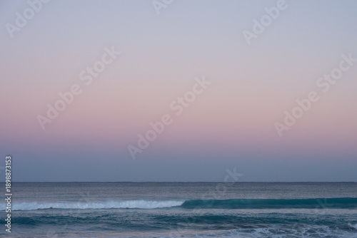 Soft pastel dawn sky over calm ocean waves