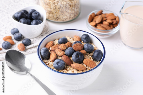 Schilderij op canvas Oat flakes, almond milk, blueberries and nuts on white wooden table, closeup