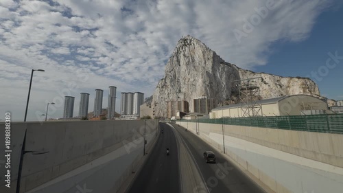 Iconic rock of gibraltar rising above the main road, surrounded by modern high-rise buildings and infrastructure