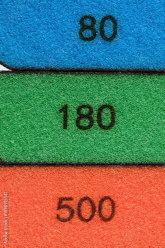 Abstract macro image three abrasive sponges blue, green, orange with clearly visible numbers grain size 80, 180 and 500.