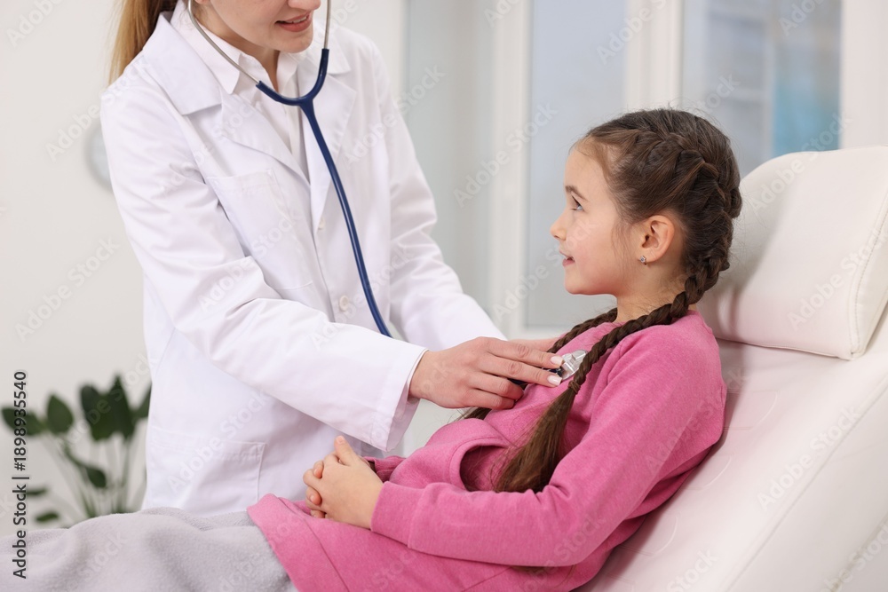 Fototapeta premium Doctor checking little girl with stethoscope in hospital, closeup