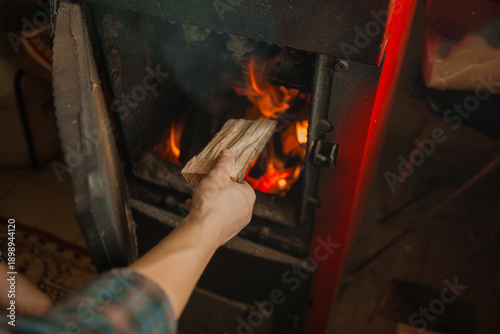 Hand placing firewood into wood burning stove