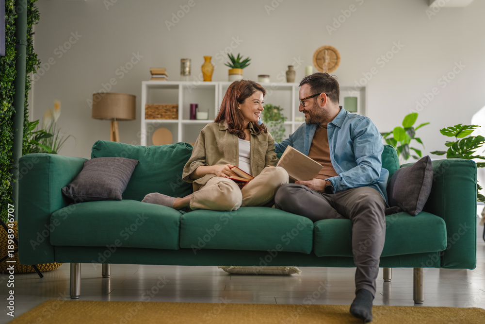 Obraz premium Couple relaxing together on sofa reading book