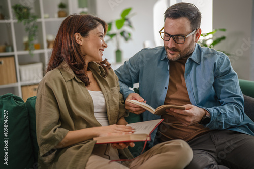 Foto Couple relaxing on sofa together reading books enjoying leisure time