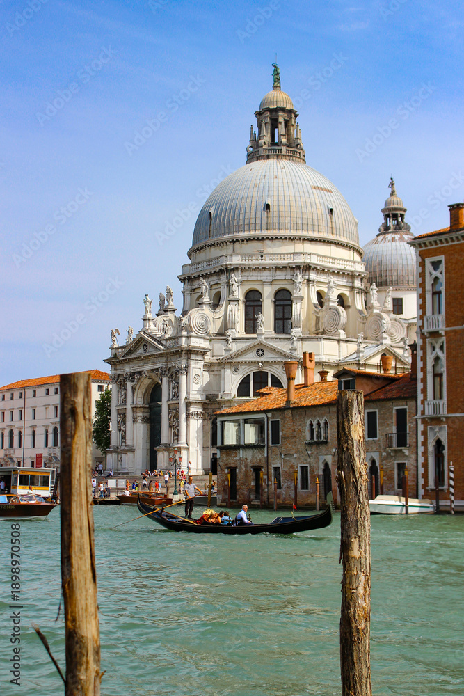 Naklejka premium Gondola on Grand Canal in Venice with Basilica Santa Maria della Salute and Historic Architecture on Sunny Day