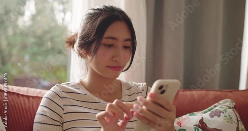 Smiling Young Asian Woman Using Smartphone on Sofa - Online Shopping and Social Media Lifestyle Concept