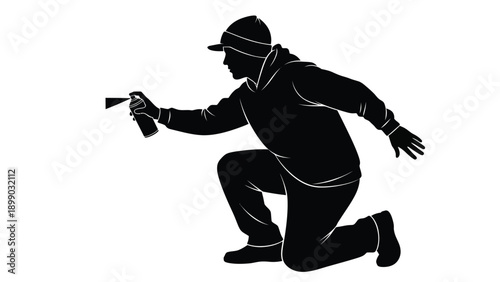 Silhouette of a person kneeling while holding and spraying aerosol paint from a can in an artistic gesture