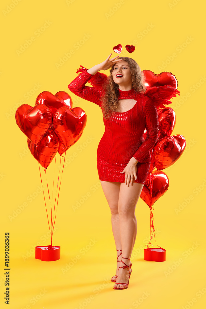 Fototapeta premium Beautiful woman dressed as Cupid with balloons on yellow background. Valentine's Day celebration