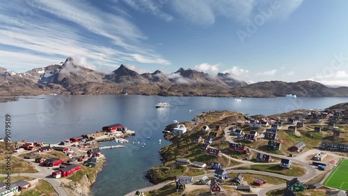 Scenic View of Tasiilaq Harbor and Mountains in East Greenland. Wide shot of Tasiilaq town and harbor in East Greenland. The footage captures the colorful wooden houses, small boats in the marin
