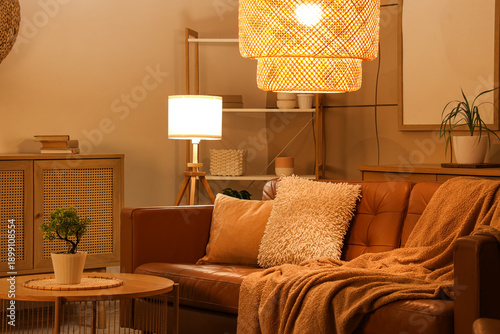 Obraz na plátně Interior of stylish living room with brown sofa, coffee table and glowing lamps