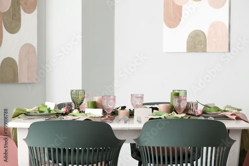 Elegant table setting with beautiful flowers and green leaves in light dining room