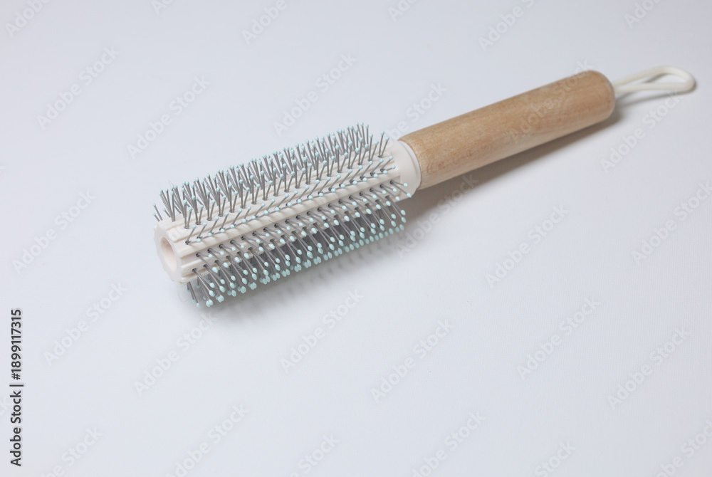 Fototapeta premium Round Hairbrush with Wooden Handle and Metallic Barrel..A professional round hairbrush featuring a cylindrical metallic barrel with evenly spaced bristles and a smooth wooden handle. 