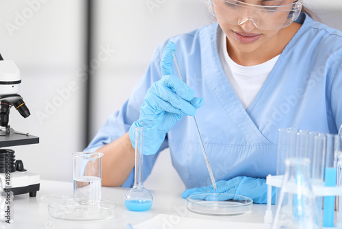 Female young scientist with professional glassware examining water quality in...