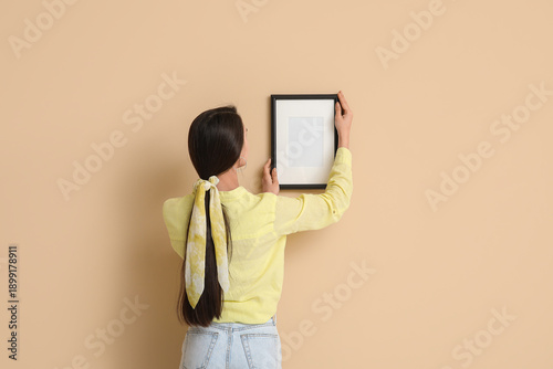 Young woman hanging picture...