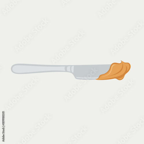 A butter knife with a smear of peanut butter on the blade is placed on a table.