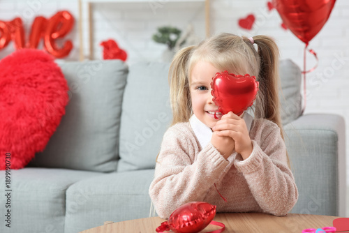 Cute little girl with heart shaped balloon in room decorated for Valentines Day