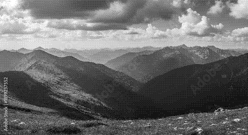 Mountain range landscape with rolling hills and cloudy sky viewed from a high vantage point in black and white photography