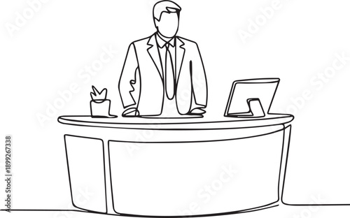Businessman standing behind modern office desk with computer and stationery viewed from the front