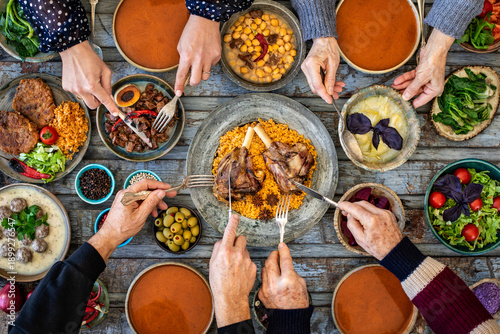 Iftar, break the fasting at holy Ramadan with family, top view of a dining table at iftar time when many human hands sharing their meal. 