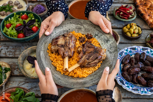 Iftar, break the fasting at holy Ramadan with family, top view of a dining table at iftar time when many human hands sharing their meal. 