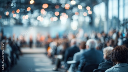 Wallpaper Mural A blurred image of an audience in a spacious venue, with blurred lights and figures, suggesting a formal event or gathering. Torontodigital.ca