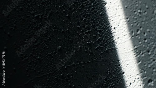 Close-up of a rough textured grey surface with small bumps and shadows from side lighting