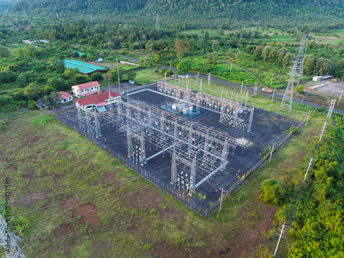 Oblique drone view of a large electrical substation with transmission towers in countryside.