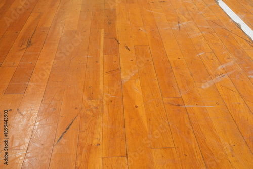 The floor is made of wood and has a worn appearance. The wood grain is visible and the floor is quite dirty