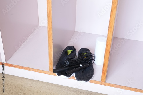 A pair of black shoes and a jump rope are sitting on a shelf. The shoes are placed on the shelf next to the jump rope, creating a sense of organization and order