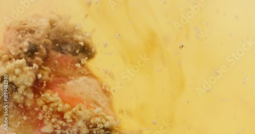 Abstract Macro Fluid Movement with Organic Particles and Pink Swirls in Yellow Liquid