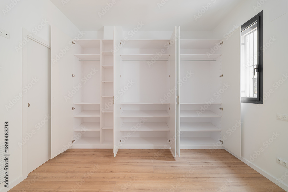 custom made wallpaper toronto digitalA large white wardrobe with opened doors showcasing interior space and shelves. Example of storage space. Natural light enters through a window.