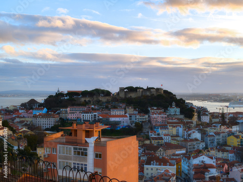 The Castelo de Sao Jorge or St George's Castle on its hill overlooking the city of Lisbon, Portugal. View from viewpoint Miradouro da Senhora do Monte before sunset. Panorama