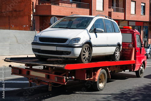 broken car in tow truck driving down in city street
