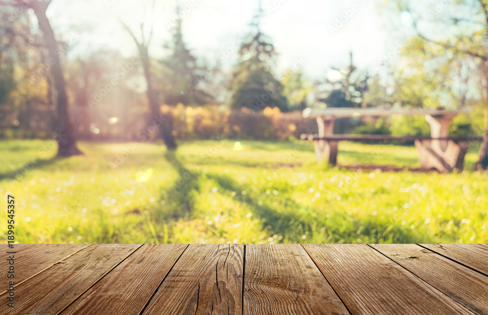 Obraz premium Wooden table and natural blurred background, picnic in sunny spring park