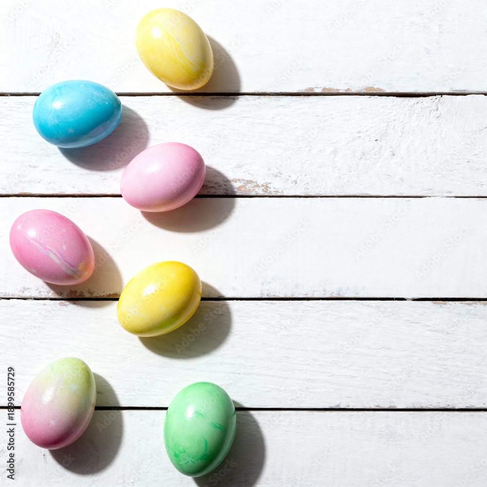 Obraz premium A basket of colorfull Eastereggs, on a white wooden background.