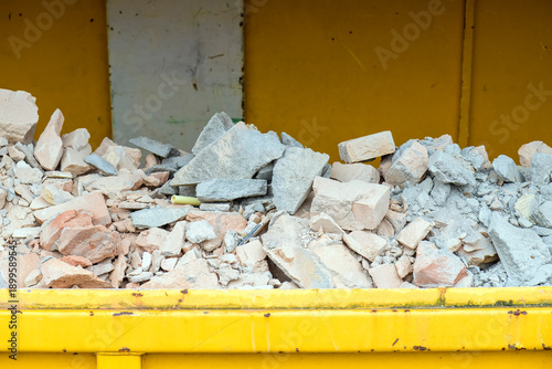 Φωτογραφία rubble is located in a yellow open industrial waste container