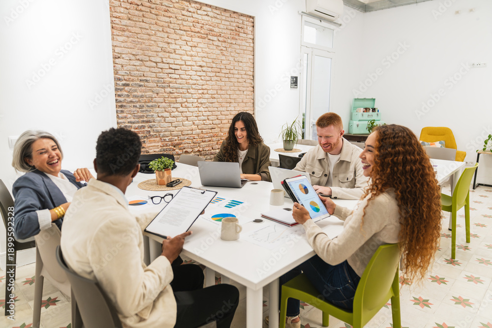 Fototapeta premium Group of happy business professionals brainstorming and analyzing data charts in a modern office workspace