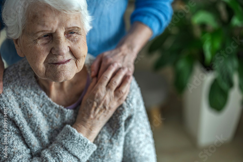 Elderly woman holding hands with her caregiver in a nursing home, close-up