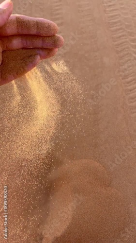 In the desert, a hand takes sand and scatters it through its fingers, a close-up of a hand with loose sand